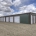 photo of grey and maroon, brand new mini storage facility, grey building with brown trim and white doors