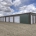photo of grey and maroon, brand new mini storage facility, grey building with red trim and white doors
