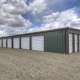 photo of grey and maroon, brand new mini storage facility, grey building with brown trim and white doors