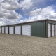 photo of grey and maroon, brand new mini storage facility, grey building with red trim and white doors