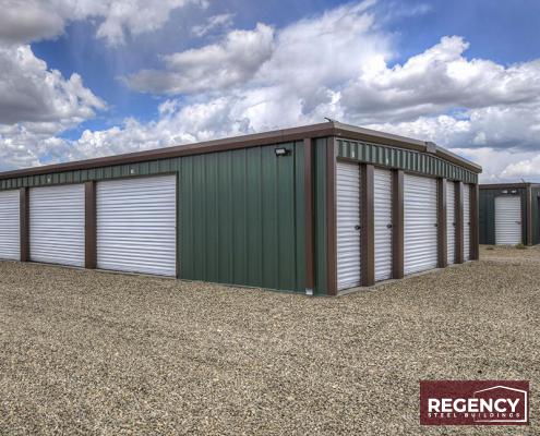 green and white mini storage building with a clouding sky