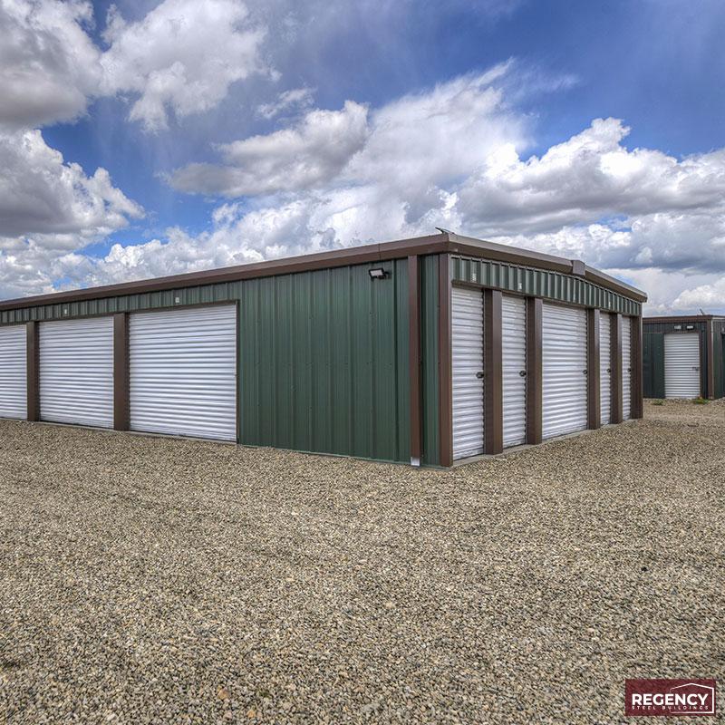 green and white mini storage building with a clouding sky